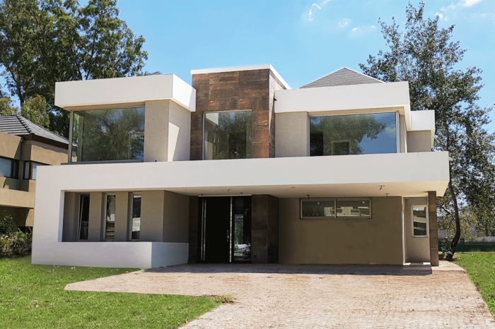 frente casa moderna con grandes ventanas barrio cerrado